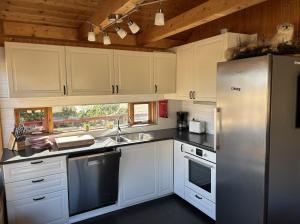 a kitchen with white cabinets and a stainless steel refrigerator at Summerhouse Torfalundur in Blönduós +15 photos