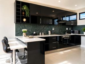 a kitchen with black cabinets and white counter tops at Movic's Modern Airbnb in Windhoek