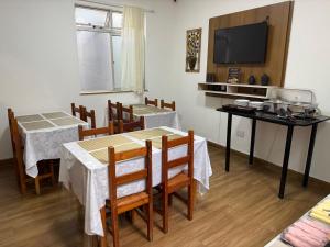 a dining room with two tables and a television at Hotel Santorine Plaza - Itabira - Próximo a Fundação Cultural Carlos Drummond Andrade in Itabira