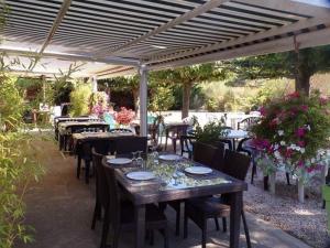 a patio with tables and chairs under a pergola at Appartement saumon 3p in Rognes