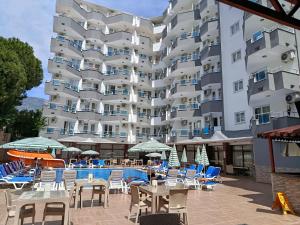ein großes weißes Gebäude mit Stühlen und einem Schwimmbad in der Unterkunft Bariscan Hotel in Mahmutlar