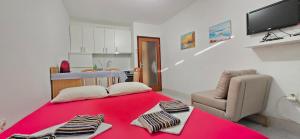 a bedroom with a red bed with a chair and a red blanket at Studio Rose in Gajac