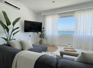 a living room with a blue couch and a large window at Elounda Port Apartment in Elounda