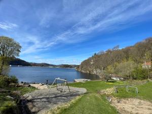a view of a lake with a swing at Apartment with great sunset view! in Lyngdal