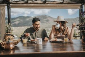 a man and woman sitting at a table eating food at Casa Misiones Glamping in Valle de Guadalupe