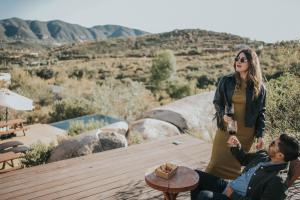 a woman standing next to a man holding a glass of wine at Casa Misiones Glamping in Valle de Guadalupe