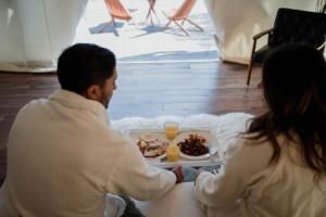a man and woman sitting at a table with a plate of food at Casa Misiones Glamping in Valle de Guadalupe +66 photos