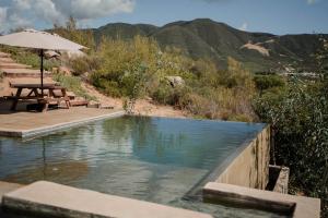 a swimming pool with a table and an umbrella at Casa Misiones Glamping in Valle de Guadalupe