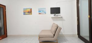 a room with a chair and a tv on a wall at Studio Rose in Gajac