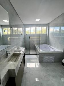 a large bathroom with a tub and a sink at Hotel Pasqualotto in Chopinzinho