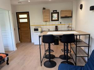 a kitchen with a table and four bar stools at Appartement refait dans ancien hôtel restaurant in Saint-Uze