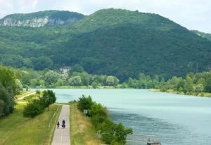 two people walking along a path next to a river at Appartement refait dans ancien hôtel restaurant in Saint-Uze +5 photos