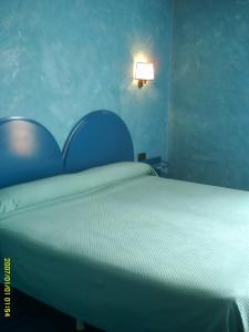 a bedroom with a bed with a blue wall at Hotel VillaPaloma in La Virgen del Camino