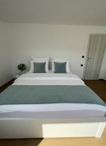 a large white bed with green and white pillows at Elounda Port Apartment in Elounda