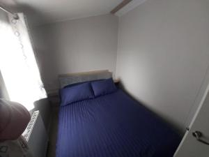 a small bedroom with a bed with blue pillows at Aquamarine Bythesea Porthcawl in Newton