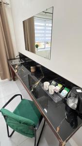 a glass desk with a mirror and a green chair at Downtown Hostel Jamaica in Kingston