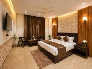 a hotel room with a large bed and a television at Hotel Sunshine in Surajpur Jikkla