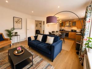a living room with a blue couch and a kitchen at Mango Tree Apartment - Near Leisure Park & Station in Cambridge