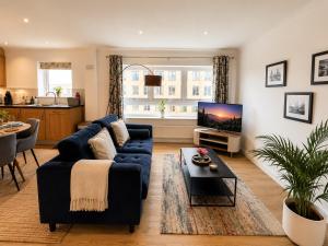 a living room with a blue couch and a tv at Mango Tree Apartment - Near Leisure Park & Station in Cambridge