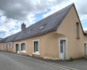a building with a pitched roof with windows on a street at La maison du petit peintre in Villaines-sous-Lucé