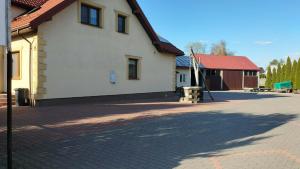 a white building with a red roof and a brick road at Agroturystyka Kuźnia in Neple