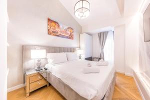 a bedroom with a large white bed with two lamps at Charma Luxury Apartment - ROMA in Rome