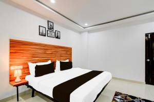 a bedroom with a large bed with a wooden headboard at Hotel O Inn In Town in Sangāreddi