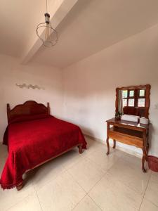 a bedroom with a red bed and a table at La casa de los Faroles in Cuetzalán del Progreso
