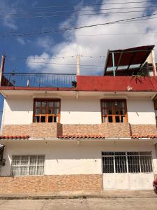 a white building with windows and a red roof at La casa de los Faroles in Cuetzalán del Progreso