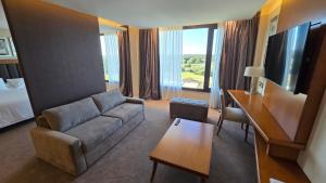 a living room with a couch and a television in a hotel room at Azahar Hotel & Spa in San Pedro