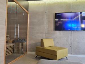 a room with a chair and a television on a wall at 74SUITE Sibenik - Self check in - Garage in Šibenik