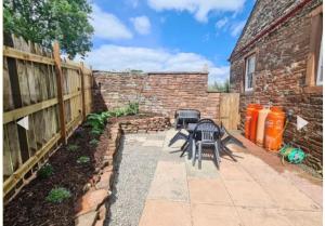 a patio with two chairs and a brick wall at Chapel House Accommodation in Culgaith
