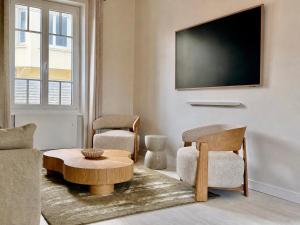 a living room with a tv and two chairs and a table at GIte de la Grande Plage in Pléneuf-Val-André