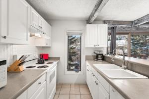 a kitchen with white cabinets and a sink at 29C by SkyRun Aspen in Snowmass Village