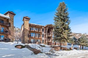 a apartment building with a christmas tree in the snow at 29C by SkyRun Aspen in Snowmass Village