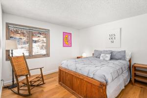 a bedroom with a bed and a chair and a window at 29C by SkyRun Aspen in Snowmass Village