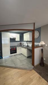 a kitchen with white cabinets and a clock on the wall at Superbe Duplex T2 62m2 - Rénové à Neuf ! in Croix
