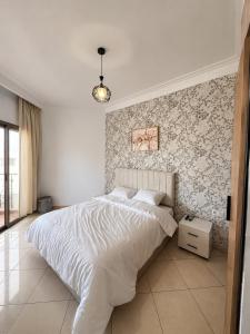 a bedroom with a white bed with a floral accent wall at Asilah Ocean View Residence in Asilah