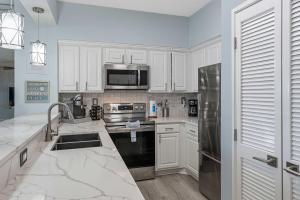a kitchen with white cabinets and a stainless steel refrigerator at TOPS'L Tides 0207 in Destin