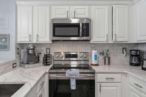 a kitchen with white cabinets and a stove and microwave at TOPS'L Tides 0207 in Destin