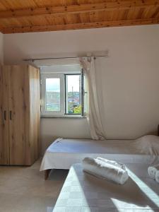 a white bedroom with a bed and a window at Liberty Home Μάκρη in Alexandroupoli