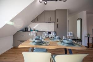a kitchen with a wooden table with plates and wine glasses at Sali Suite - Modern Attic Stay in Arbon