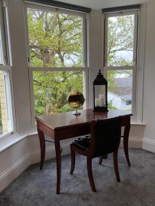 a desk with a lamp and a chair in front of a window at Martris House in Rhayader