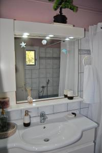 ein Badezimmer mit einem weißen Waschbecken und einem Spiegel in der Unterkunft Amalia's Maisonette in Marathos + 40 Fotos