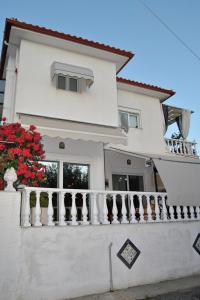 ein weißes Haus mit einem Balkon mit roten Blumen in der Unterkunft Amalia's Maisonette in Marathos
