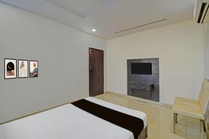 a bedroom with a bed and a chair and a television at Hotel O Madhuram Lodge in Siddipet