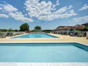 a blue swimming pool with chairs and a blue sky at Camping Olé camp in Balazuc