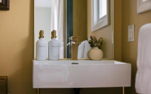 a bathroom sink with three bottles on it in front of a mirror at Gale River House - Boutique Hotel in Franconia