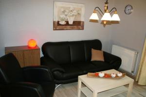 a living room with a black couch and a table at Ferienwohnung Lüneburger Heide in Schneverdingen