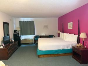 a bedroom with a large bed and a pink wall at UP NORTH HOTEL formerly Voyager Inn in Saint Ignace